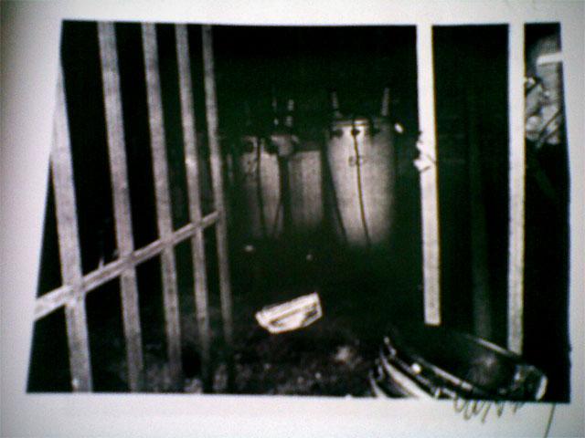 Fotografía blanco y negro  en el expediente del caso del lugar donde murio electrocutada Karen Yamileth Cordero, de 24 años, en el Súper Selectos de Mejicanos. La fotografía muestra los transformadores de alto voltaje del negocio protegidos con una reja con candado que según la versión de familiares fue encerrada durante 45 minutos y según la parte acusada del crímen, la víctima entro voluntariamente mientras intentaba huir por haber sido sorprendida robando café y pasta dental con el valor de 27 dólares.