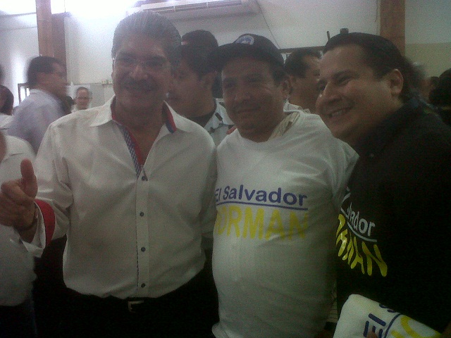 El alcalde capitalino, Norman Quijano, posa para una fotografía junto a dos simpatizantes que visten camisetas donadas por un amigo empresario.