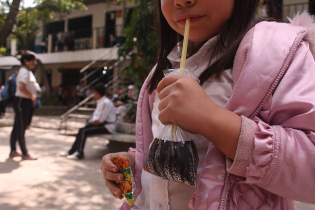 Una alumna del Complejo Educativo Walter Soundy, de Santa Tecla, toma su refrigerio consistente en una Coca Cola y comida chatarra.