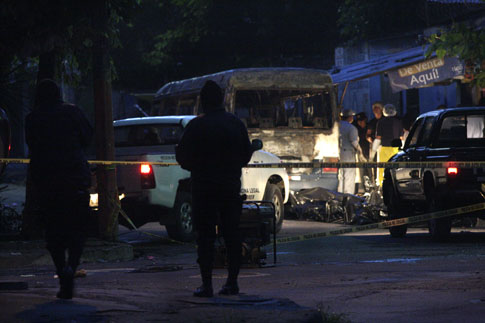 Vehículos de Medicina Legal se alistan para llevarse 14 cuerpos quemados colocados en bolsas plásticas en la colonia Jardín de Mejicanos.