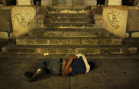 Una persona en estado de ebriedad duerme al pie del Monumento a los Próceres en la plaza Libertad de San Salvador. Foto Frederick Meza
