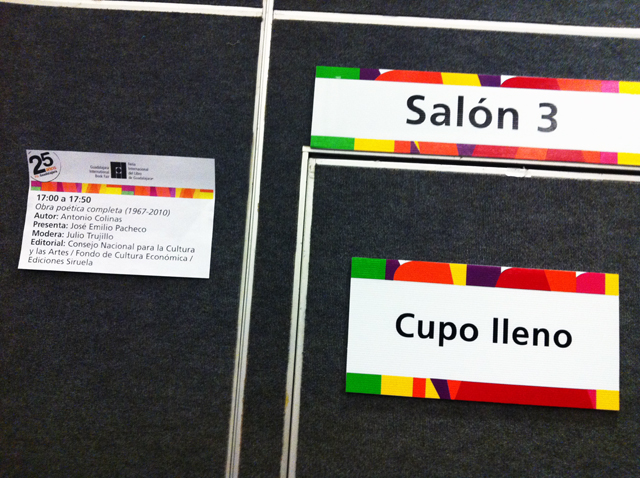 El cartel izquierdo anuncia presentación de la obra poética de Antonio Colinas por José Emilio Pacheco, dos leyendas que abarrotan el salón / Foto de Élmer Menjívar ﻿" /></div> <figcaption class=