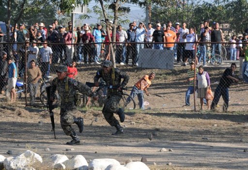 Militares que custodian la entrada a la penitenciería son atacados con piedras por los parientes de los reos después que las autoridades leyeran un listado de sobrevivientes. Foto AFPl