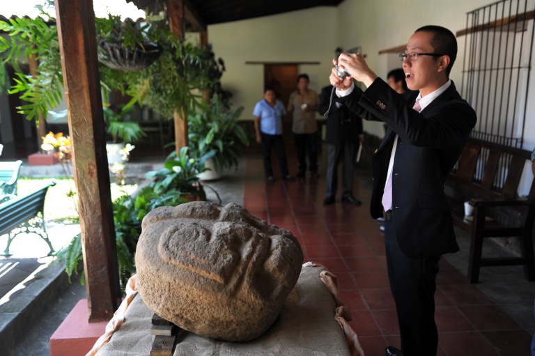 Un arqueólogo japonés toma fotografías de las cabezas descubiertas en una finca cafetalera de Chalchuapa, en Santa Ana. Foto José Cabezas (AFP)﻿