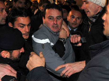 Massimo Tartaglia, de 42 a&ntilde;os, que seg&uacute;n la polic&iacute;a italiana es sospechoso de arrojar un objeto contra la cara del primer ministro Silvio Berlusconi, es sujetado por varias personas en Mil&aacute;n