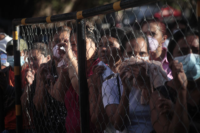 Familiares de reos de la penitenciería de Comayagua esperan noticias sobres sus familiares en la cerca perimetral de la cárcel.