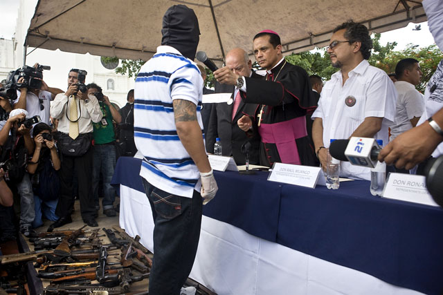 El obispo castrense Fabio Colindres ofrece el micrófono a un pandillero que declaró que la entrega de armamento es la confirmación de un proceso de pacificación de las pandillas.﻿" /></div> <figcaption class=