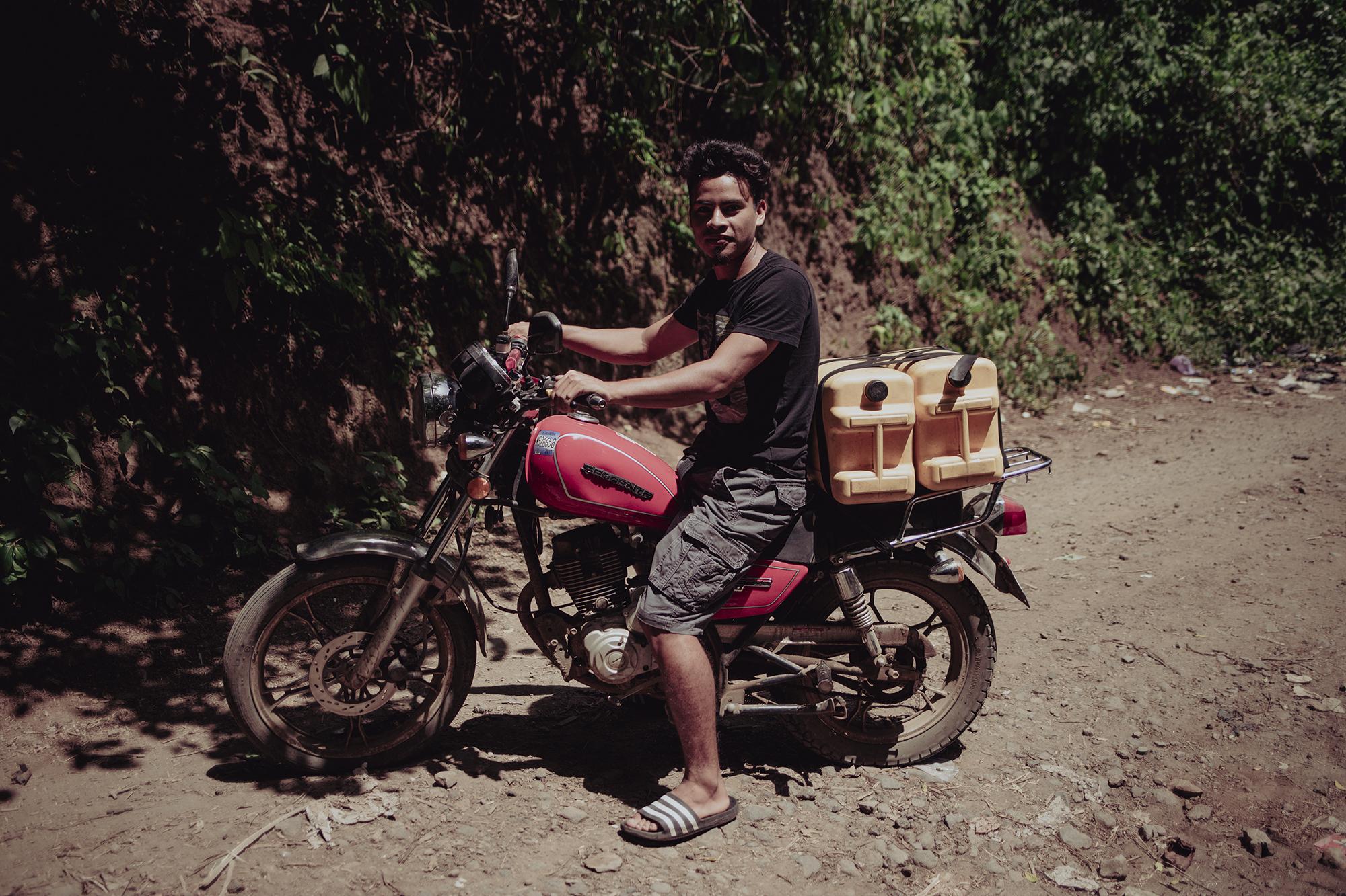 Melvin Alvarenga travels by motorcycle every two days to a water source in the canton of Las Delicias. The Alvarenga family uses the spring water exclusively for drinking. Photo: Carlos Barrera/El Faro.