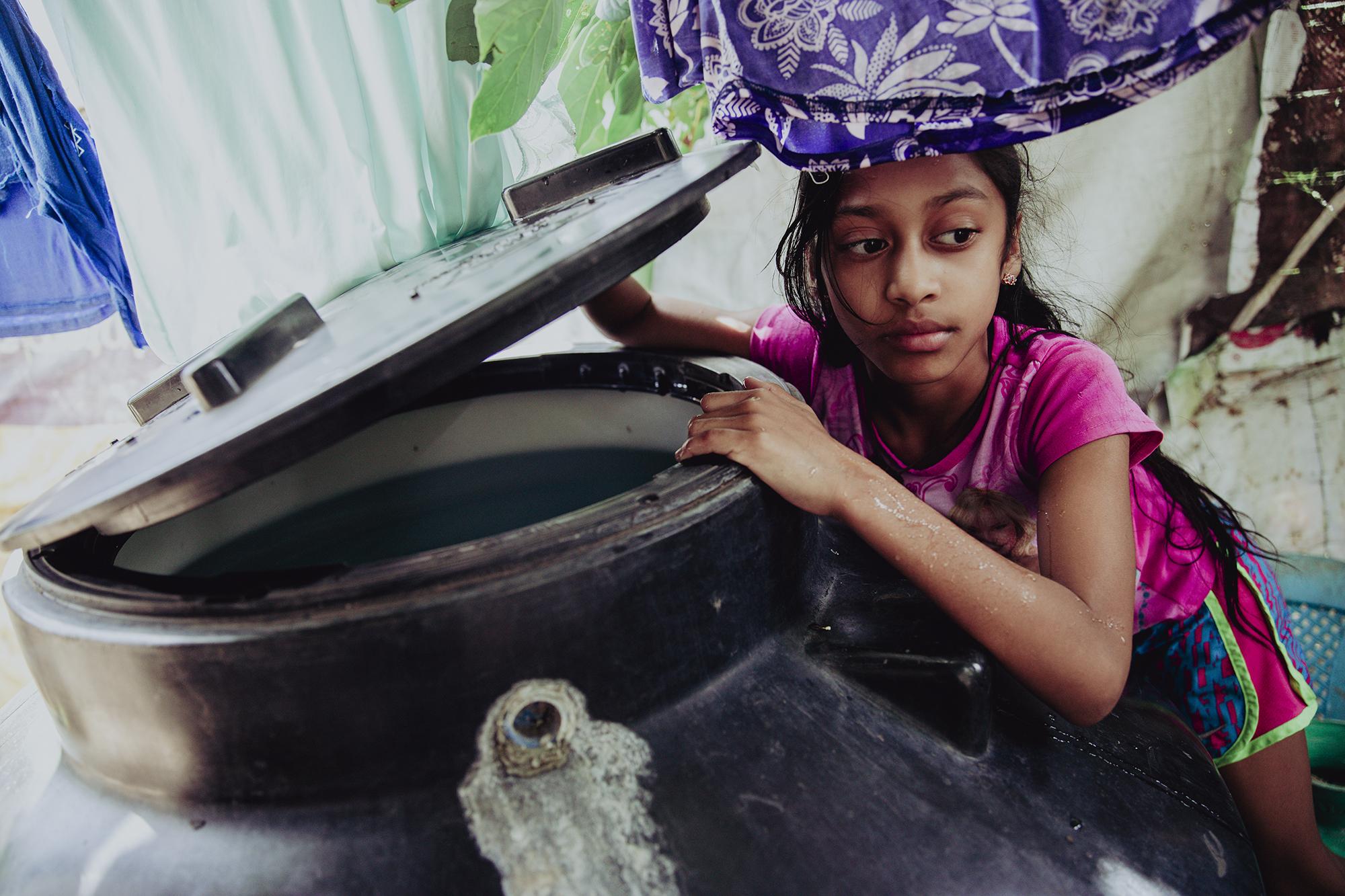 Nine-year-old Janette Guevara checks the water level of a storage barrel at her house. Water storage tanks and barrels are a common sight throughout the communities surrounding Berlín due to the unreliable potable water supply. Photo: Carlos Barrera/El Faro.